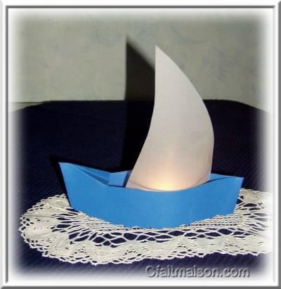 Photophore en forme de bateau avec voile en papier calque et bougie allume.